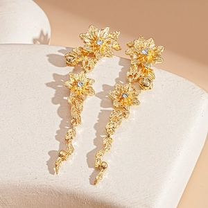 Detail of gold flower earrings with sparkling rhinestone centers and leafy metal branches