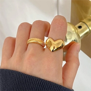 Close-up of a 925 sterling silver heart ring and textured gold band on model hand