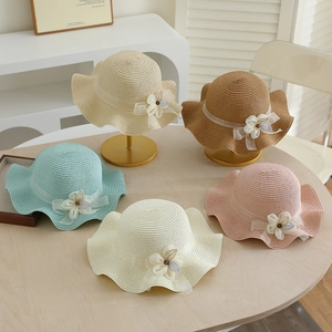 Detail of straw sun hats with floral lace decorations on a wooden table display