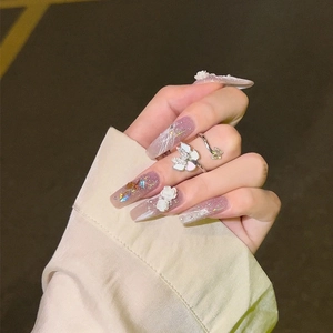 Detail of pink gradient press-on nails with white 3D flowers and silver glitter accents