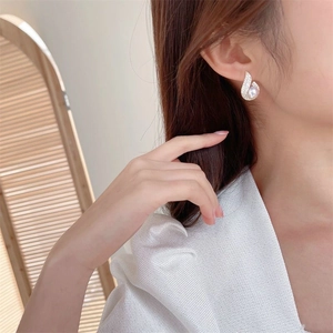 Detail of drop-shaped pearl earrings with pavé crystals on a model's ear
