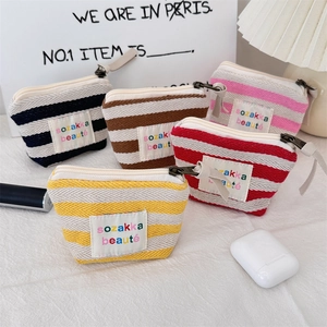Detailed arrangement of striped canvas makeup bags with metal zippers in five vibrant colors
