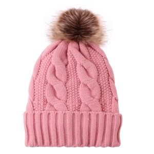 Detail of pink knitted winter beanie featuring a fluffy brown faux fur pom-pom
