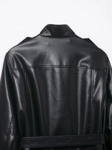 Detail der schwarzen Kunstlederjacke mit Schulterklappen, Stehkragen und Gürtel an der Taille