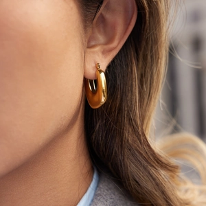 Boucles d'oreilles créoles en U en acier inoxydable plaqué or 18K portées par un mannequin