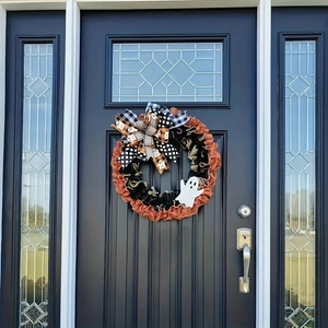 Detail of Halloween ghost wreath with orange and black burlap bows on a dark blue door