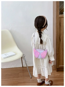 Pink sequin angel wing crossbody bag for girls shown on model in a soft indoor setting