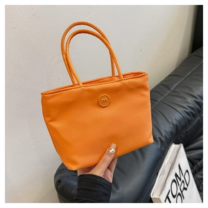 Détail d'un mini sac cabas orange en nylon avec doubles anses et logo rond m