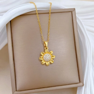 Detailed close-up of a sunflower pendant necklace with zircon pavé on a beige jewelry box