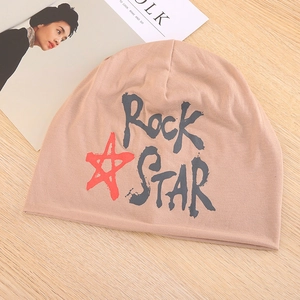 Detail van de gebreide khaki muts met rode ster en zwarte Rock Star print op hout