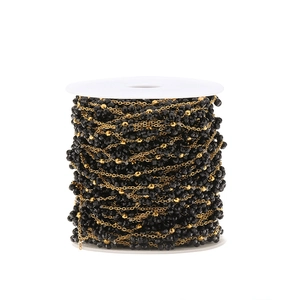 Detail of DIY jewelry chain with black beads on a white spool for craft making