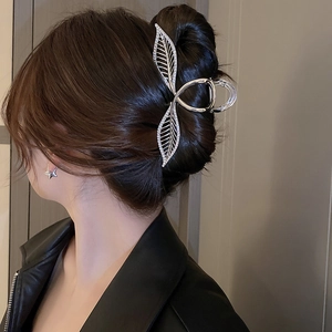 Pince à cheveux feuille argentée avec strass portée sur un chignon élégant de côté
