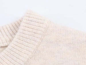 Close-up of ribbed knit neckline on a creamy white sweater with soft texture details