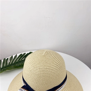 Détail d'un chapeau de paille tressé avec ruban bleu marine et texte blanc