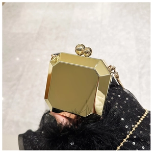 Detail of golden geometric evening clutch bag with spherical clasp and metal chain strap