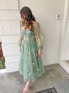 Detail view of sage green mesh evening dress with floral embroidery and bustier top
