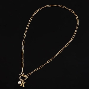 Detail of gold paperclip chain necklace with K letter pendant, toggle clasp and pearl