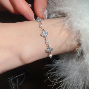 Close-up of elegant zircon flower and pearl bracelet on wrist with feather detail