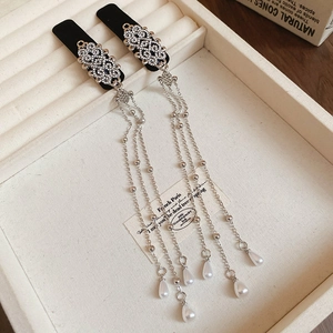 Close-up of silver tassel earrings with crystal rhinestones and white teardrop pearls