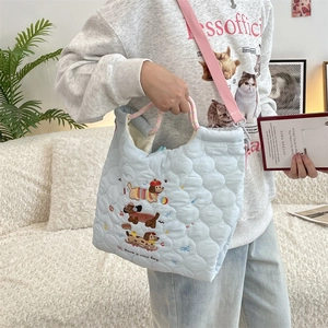 Detail of light blue quilted tote bag with cute cartoon dog embroidery and pink strap