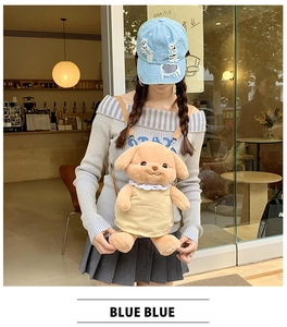 Brown plush dog backpack with yellow dress worn by a model in a cozy cafe setting