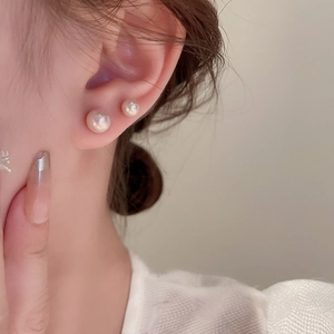 Detailed view of dual pearl earrings featuring lustrous round white pearls on model