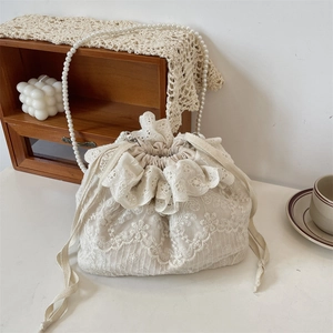 Detail der weißen Spitzenbeuteltasche mit Rüschen und langer Perlenperlenkette