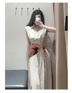 Detail of ethnic pattern silk scarf tied around waist of a sleeveless off-white dress