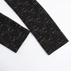 Close-up of black floral lace texture and skin-toned lining on a fitted jumpsuit