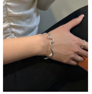 Detail showing wavy texture of silver bangle and matching ring on model wrist