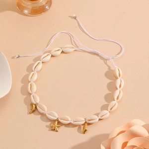 Detail of natural white shell necklace with gold starfish and dolphin charms on beige base