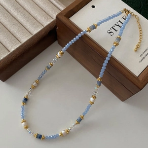 Detail of light blue faceted crystal beads and pearls on a necklace with lobster clasp