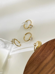 Ensemble de quatre bagues dorées ajustables avec détails de cœur, fleur et strass carrés