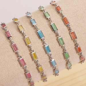 Gros plan de bracelets en zircon coloré rose, jaune et bleu sur un présentoir beige doux