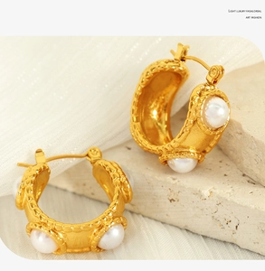 Detail view of 18k gold plated C-shaped hoop earrings featuring inlaid white pearl beads