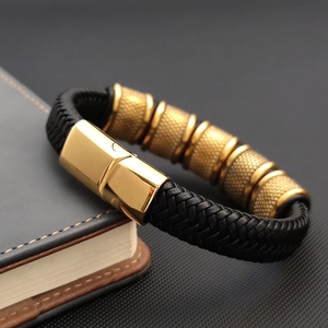 Detail of knurled golden metal rings and magnetic clasp on braided black leather bracelet