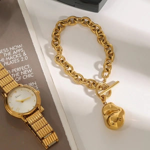 Close-up of gold chunky chain bracelet with irregular metal pendant and OT buckle
