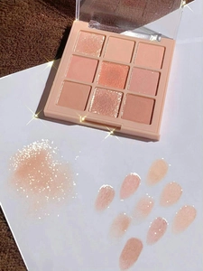 Close-up of nine-color eyeshadow palette showing matte and glitter arm swatches