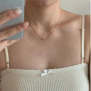 Mirror selfie showing the minimalist golden bow pendant necklace with a fine chain