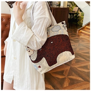Close-up of a large canvas tote bag with a red elephant print worn over the shoulder