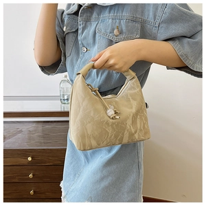 Detail of beige soft texture handbag with knot design and pearl bead embellishment