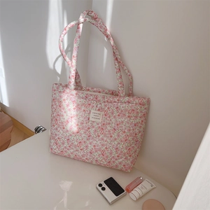 Detail of pink floral quilted tote bag with french text label and padded cotton texture