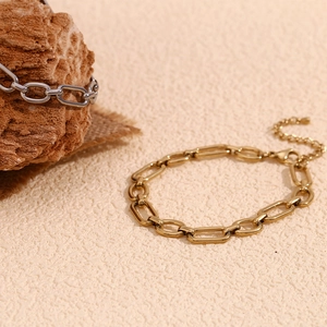 Detail of 14K gold and silver paperclip chain anklets with lobster clasp on a stone base