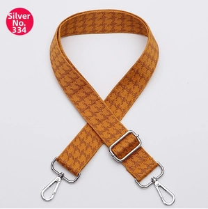 Close-up of mustard and brown houndstooth woven bag strap with silver metal buckles