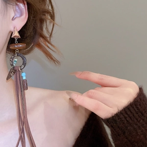 Detail of bohemian fringe earrings with wooden rings and brown leather tassels worn by a model