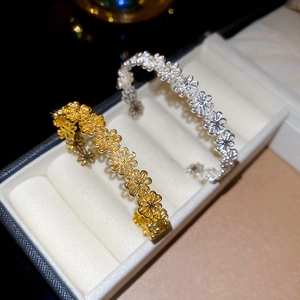Detailed view of cutout daisy patterns on gold and silver minimalist open cuff bracelets