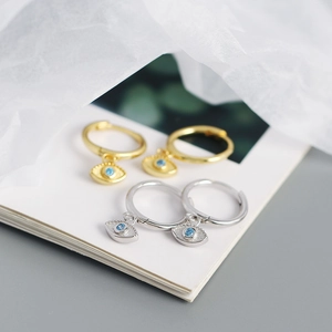 Macro shot of gold and silver S925 sterling silver hoop earrings with blue stone evil eyes