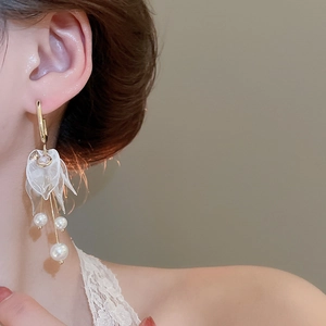 Detail of elegant gold tassel earrings with acrylic petals and white pearls on model