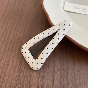 Vista dettagliata della clip per capelli triangolare con tessuto bianco a pois neri