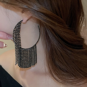Close-up of black fringe hoop earrings featuring sparkling rhinestones on a female model